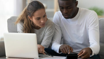 Mixed race couple reading about the differences between debt review and debt mediation in South Africa