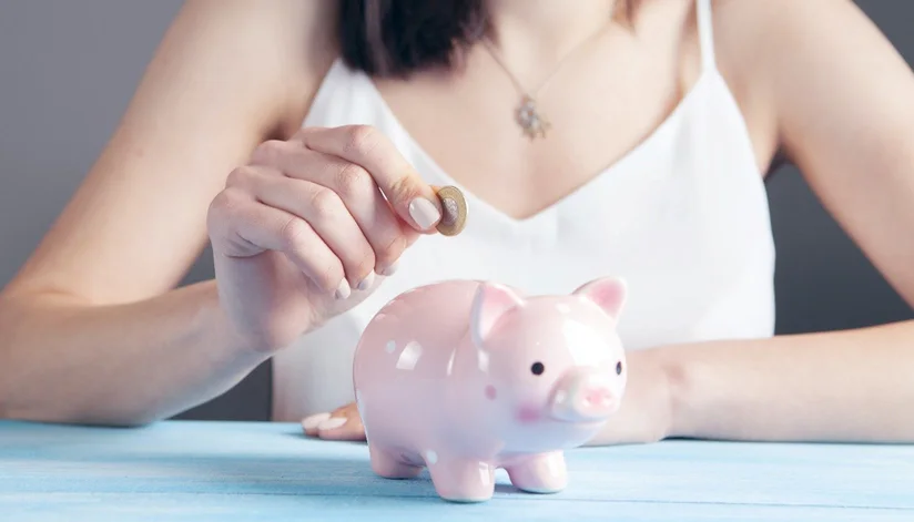 Women placing coin into piggy bank